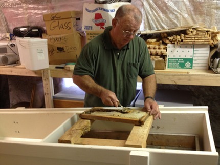 A Four B’s Farm beekeeper uncapping a frame of local honey